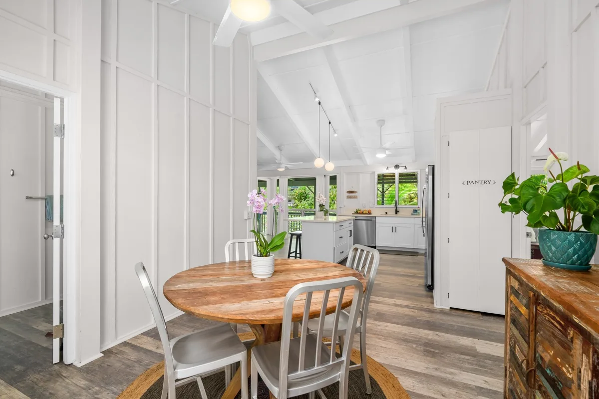 Una cocina y comedor luminosos con una mesa redonda de madera y gabinetes blancos.