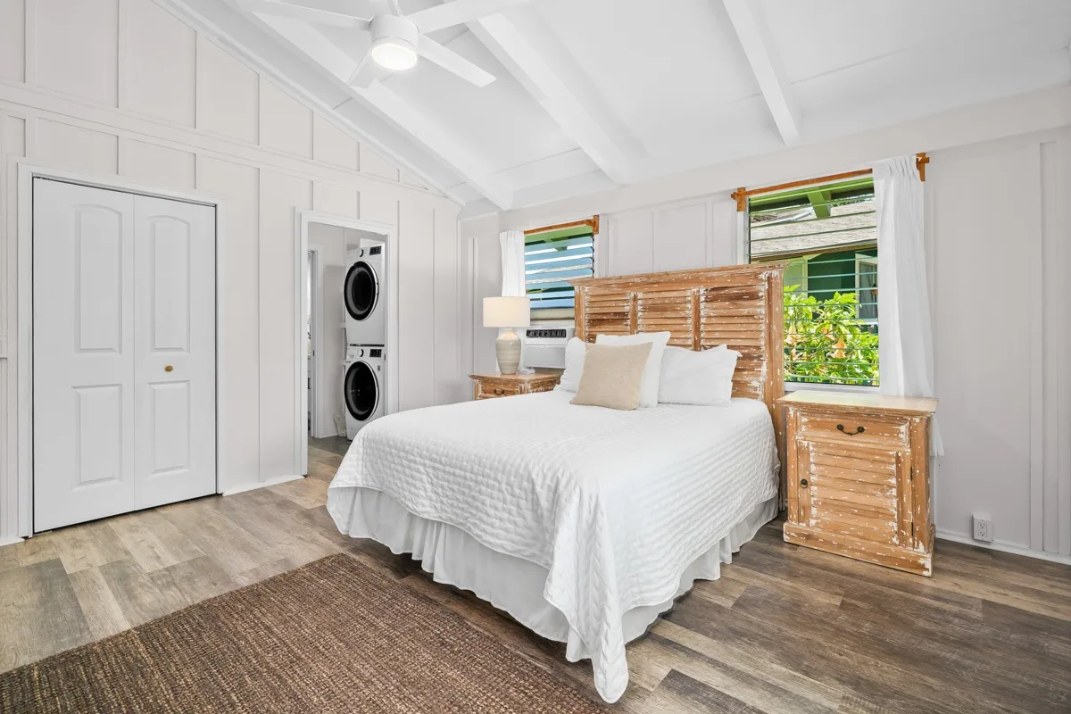 Un dormitorio luminoso con cama, cabecero tejido y lavadoras.