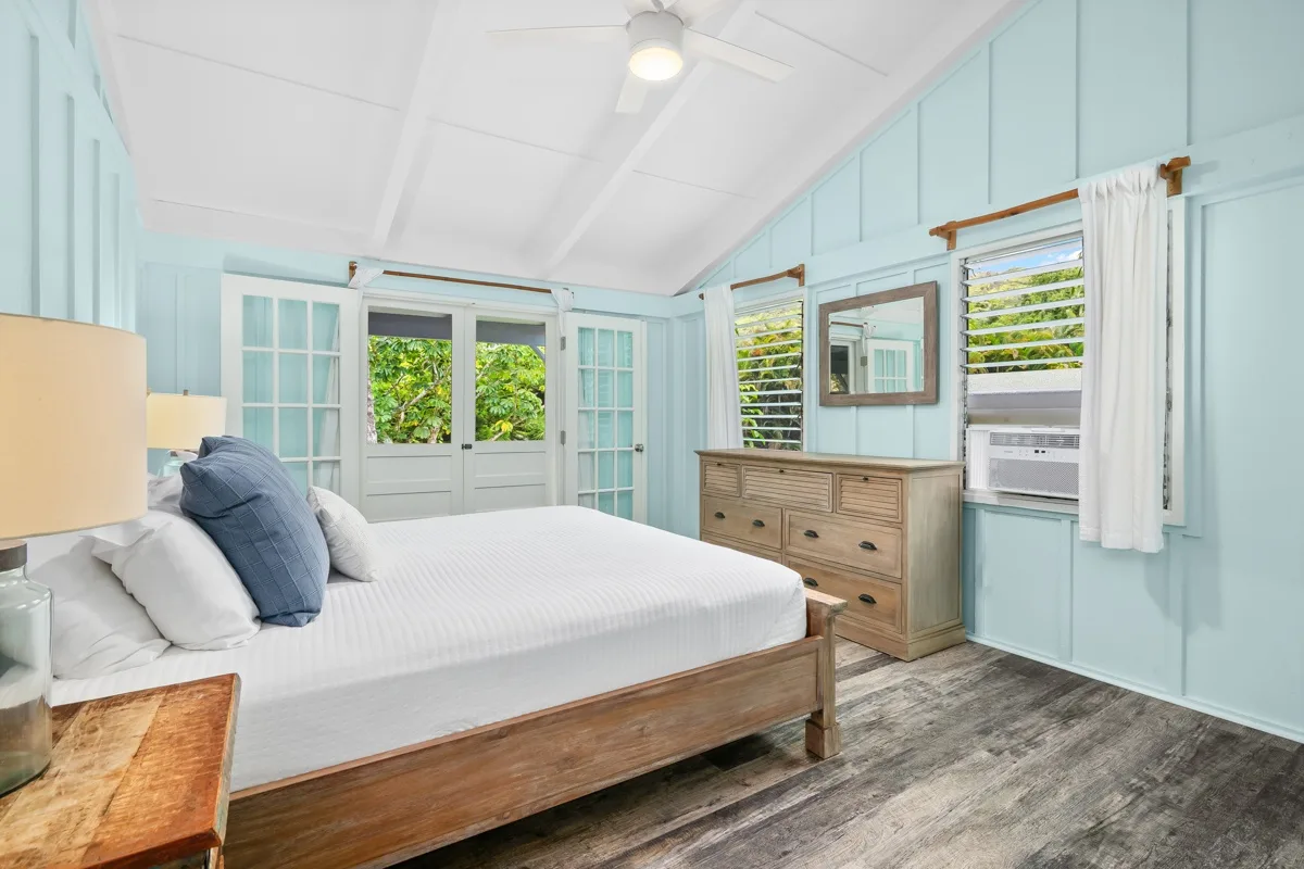 Un dormitorio luminoso con una cama de madera y paredes azul claro.