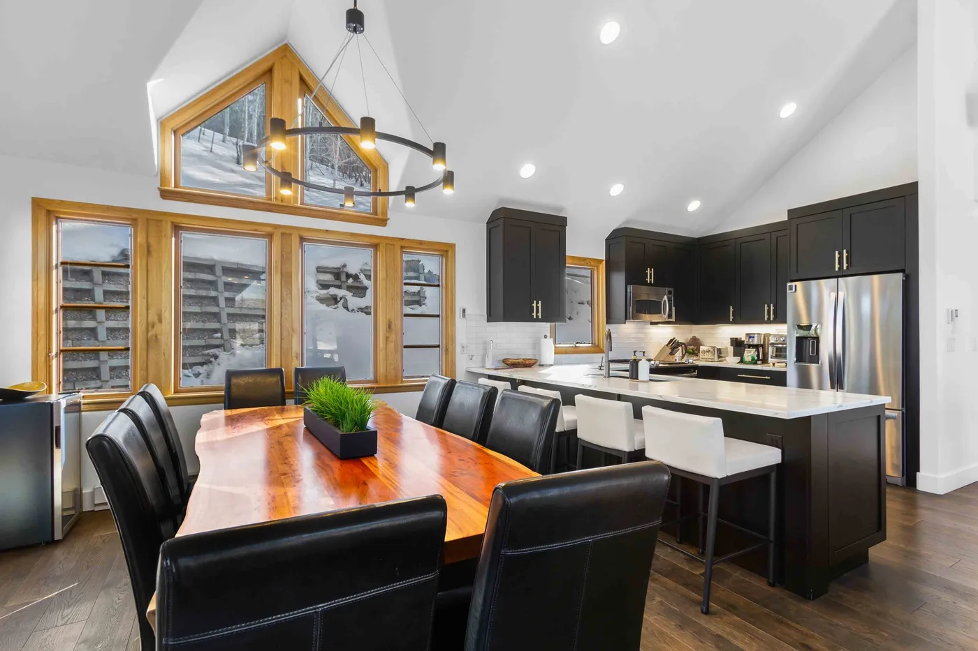 Comedor con una mesa larga de madera junto a una isla de cocina.