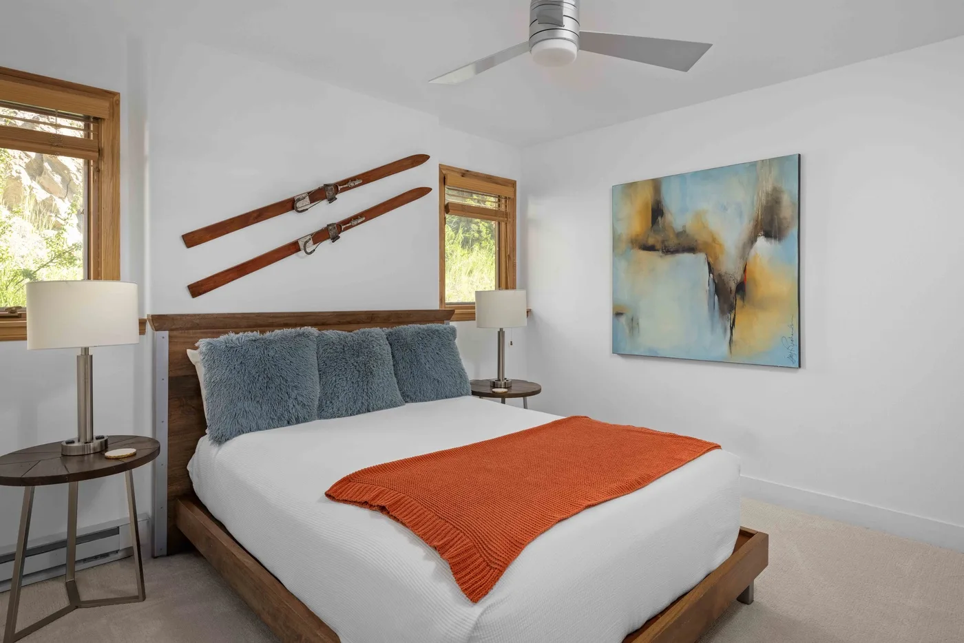 Un dormitorio con una cama, almohadas azules y una pintura abstracta en la pared.