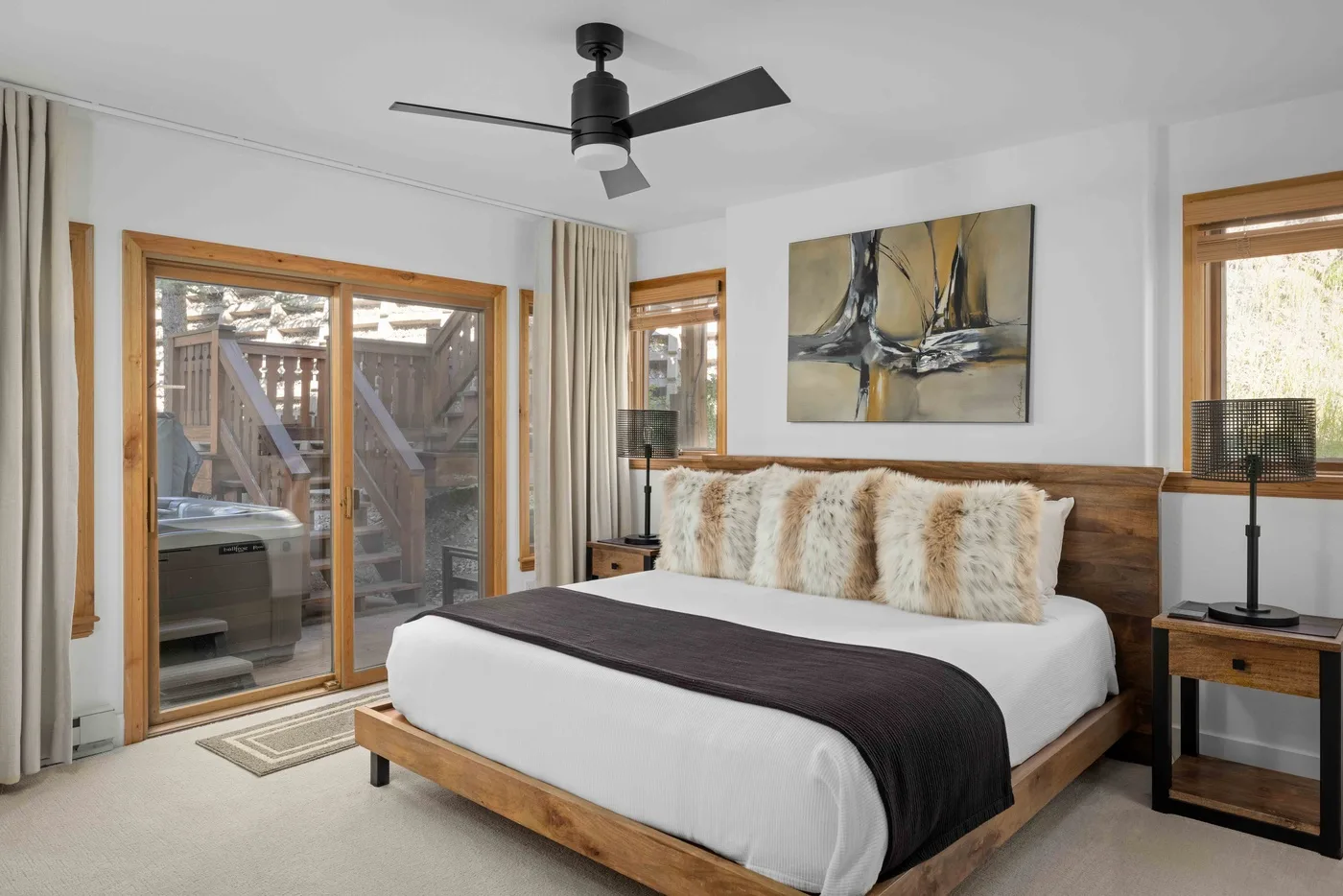Un dormitorio con una cama de madera, ropa de cama blanca y ventanas con vistas a una terraza exterior.