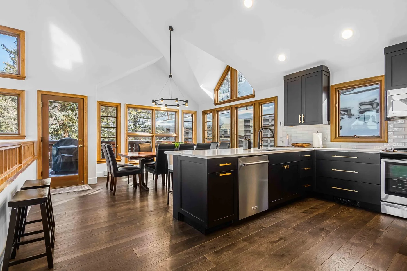A bright kitchen with dark cabinets, a central island, and large windows.