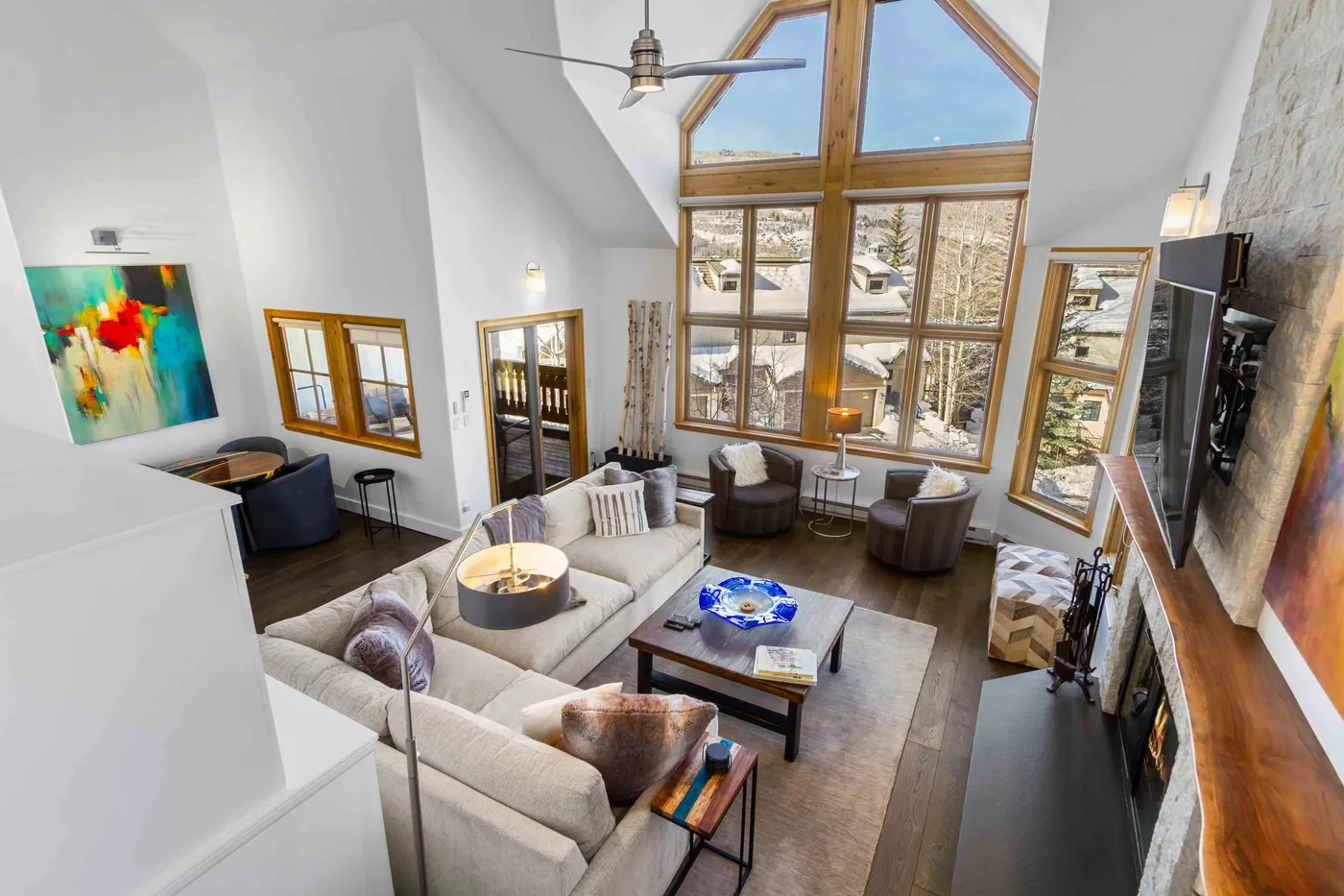 A bright living room with seating arranged around a coffee table and tall windows.