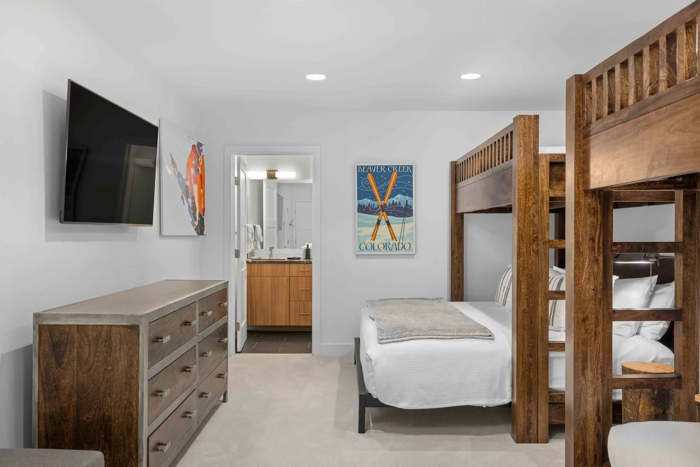 Un dormitorio luminoso con literas de madera, una cama individual y una cómoda.
