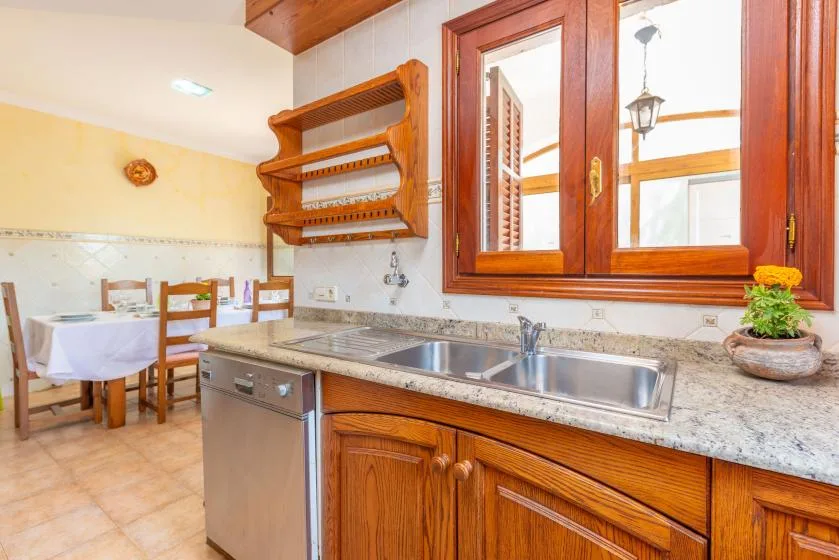 Una cocina con un fregadero de acero inoxidable y una mesa de comedor al fondo.