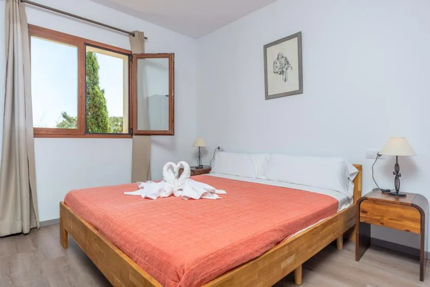 Un dormitorio con una cama de madera, ropa de cama coral y una ventana.