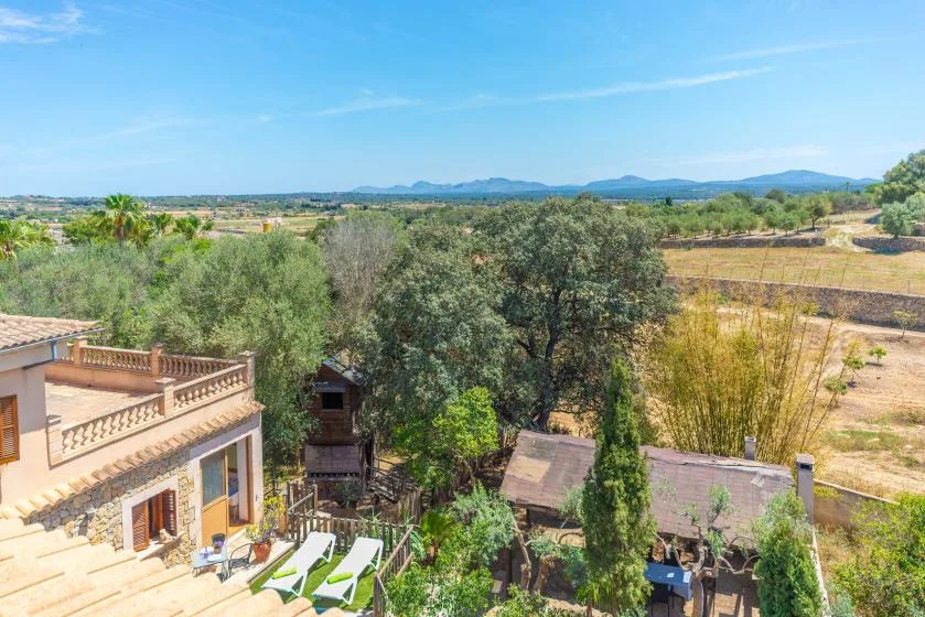 Una terraza rural tiene vistas a árboles, campos y colinas lejanas.