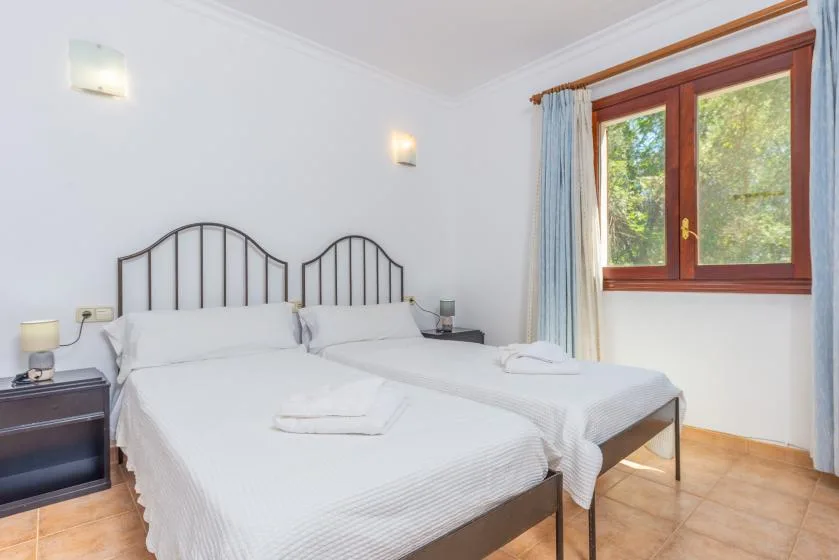 Un dormitorio luminoso con dos camas y una ventana grande.