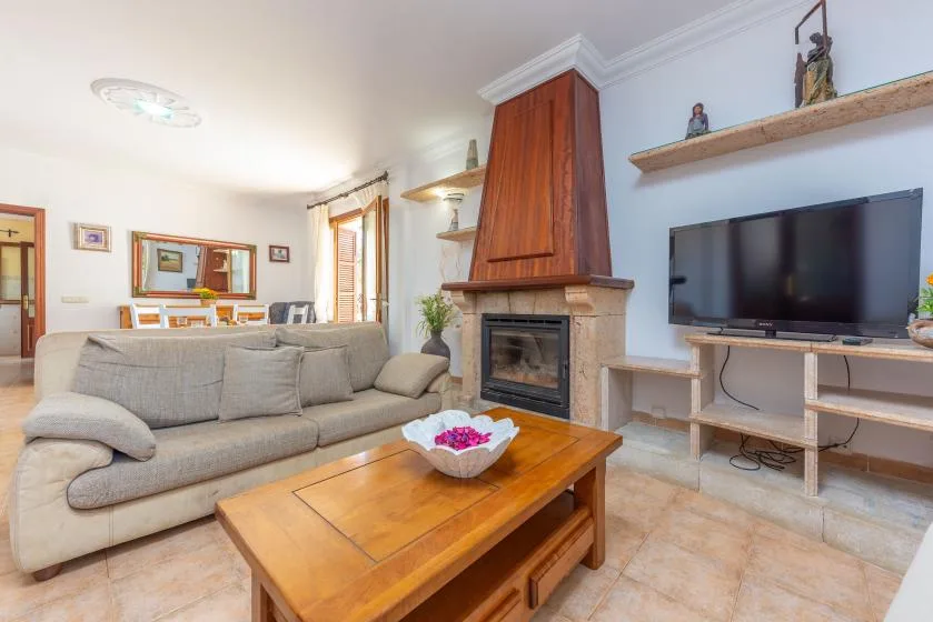 Una sala de estar con asientos, una mesa de centro de madera, un televisor y una chimenea.