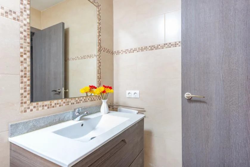 Un lavabo de baño con flores junto a un espejo.