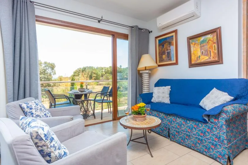 Una sala de estar con asientos azules junto a una puerta corrediza de vidrio que da a un balcón.