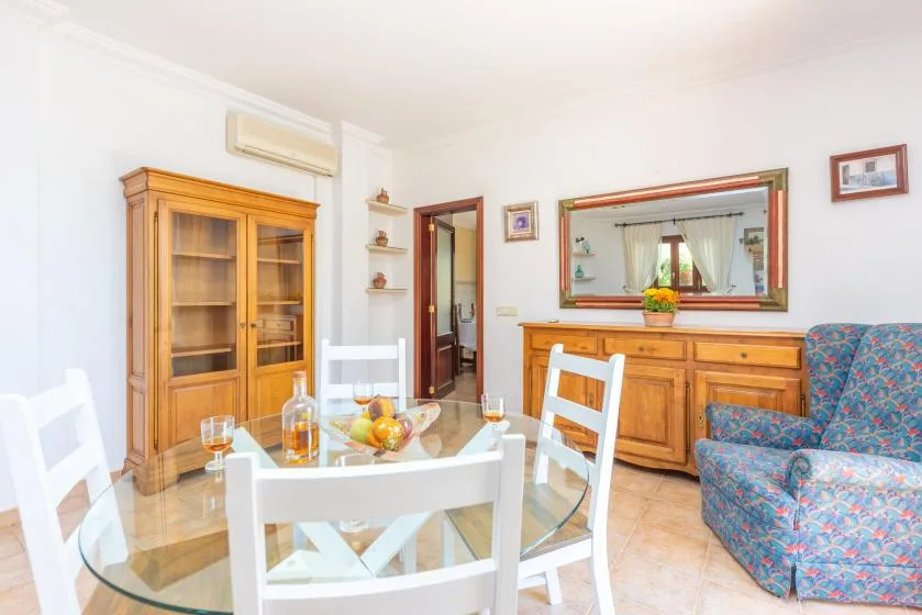 Un comedor con asientos blancos, una mesa de cristal y muebles de madera.