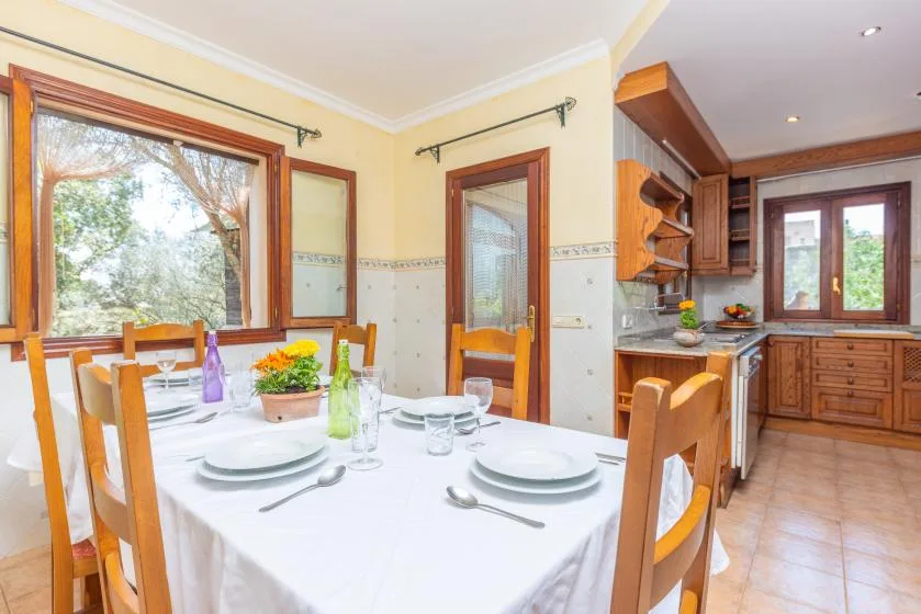 Un comedor con la mesa puesta junto a una cocina.