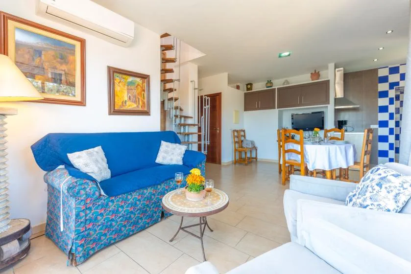 Una sala de estar y comedor con asientos azules, una mesa pequeña y una mesa de comedor.