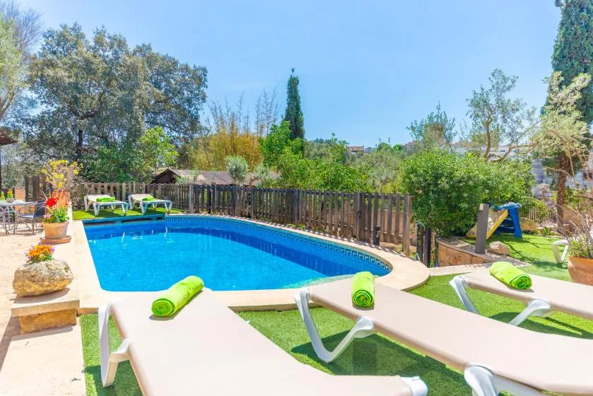 Una piscina en el patio está rodeada de tumbonas y vegetación.