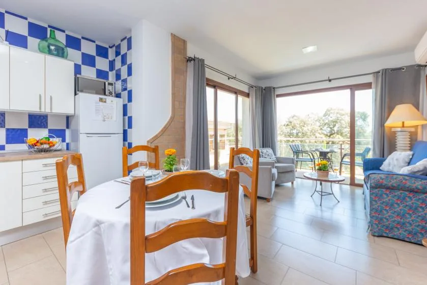 Una zona de comedor y estar se abre a un balcón mediante grandes puertas de vidrio.