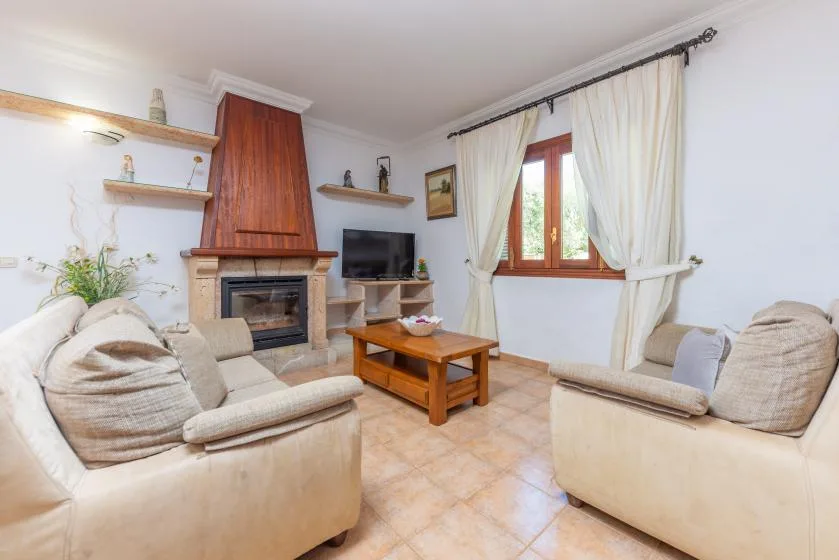Una sala de estar con asientos claros, una chimenea y una mesa de centro de madera.