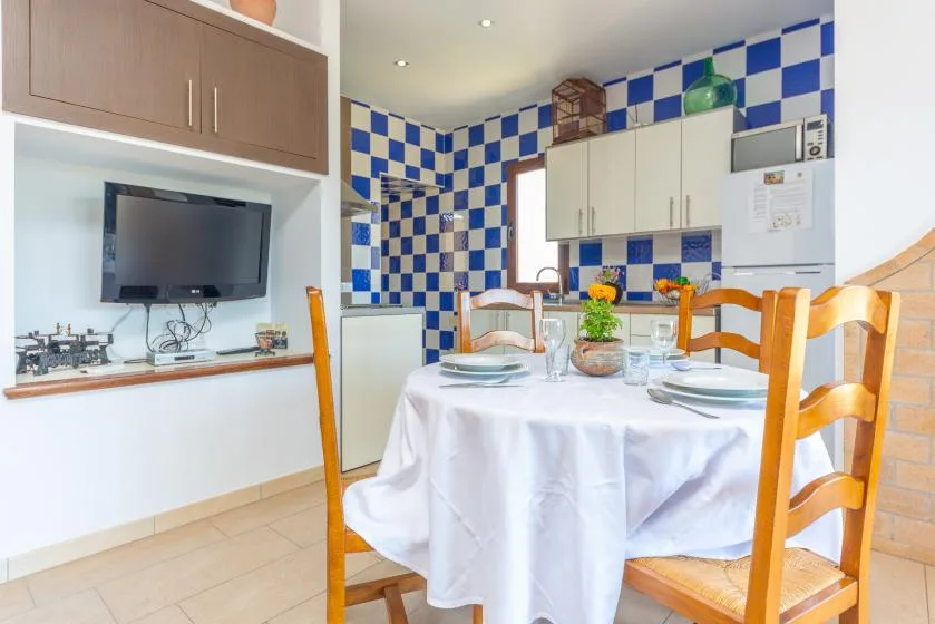 Una cocina y comedor con una mesa redonda preparada para comer.