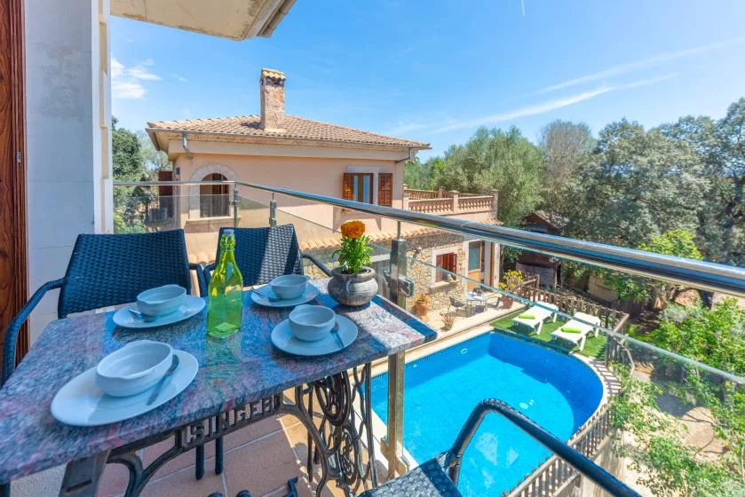 Una zona de comedor en el balcón da a una piscina y una casa cercana.