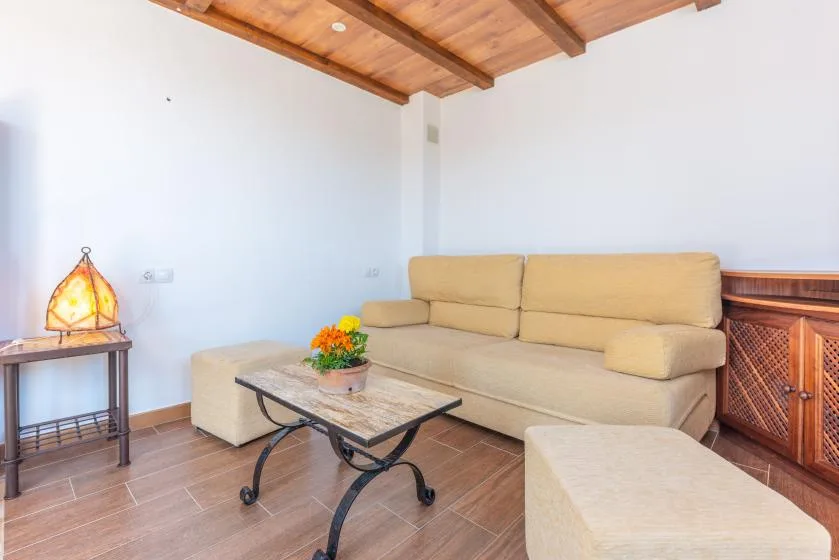 Una sala de estar con asientos beige, una mesa de centro y techo de madera.