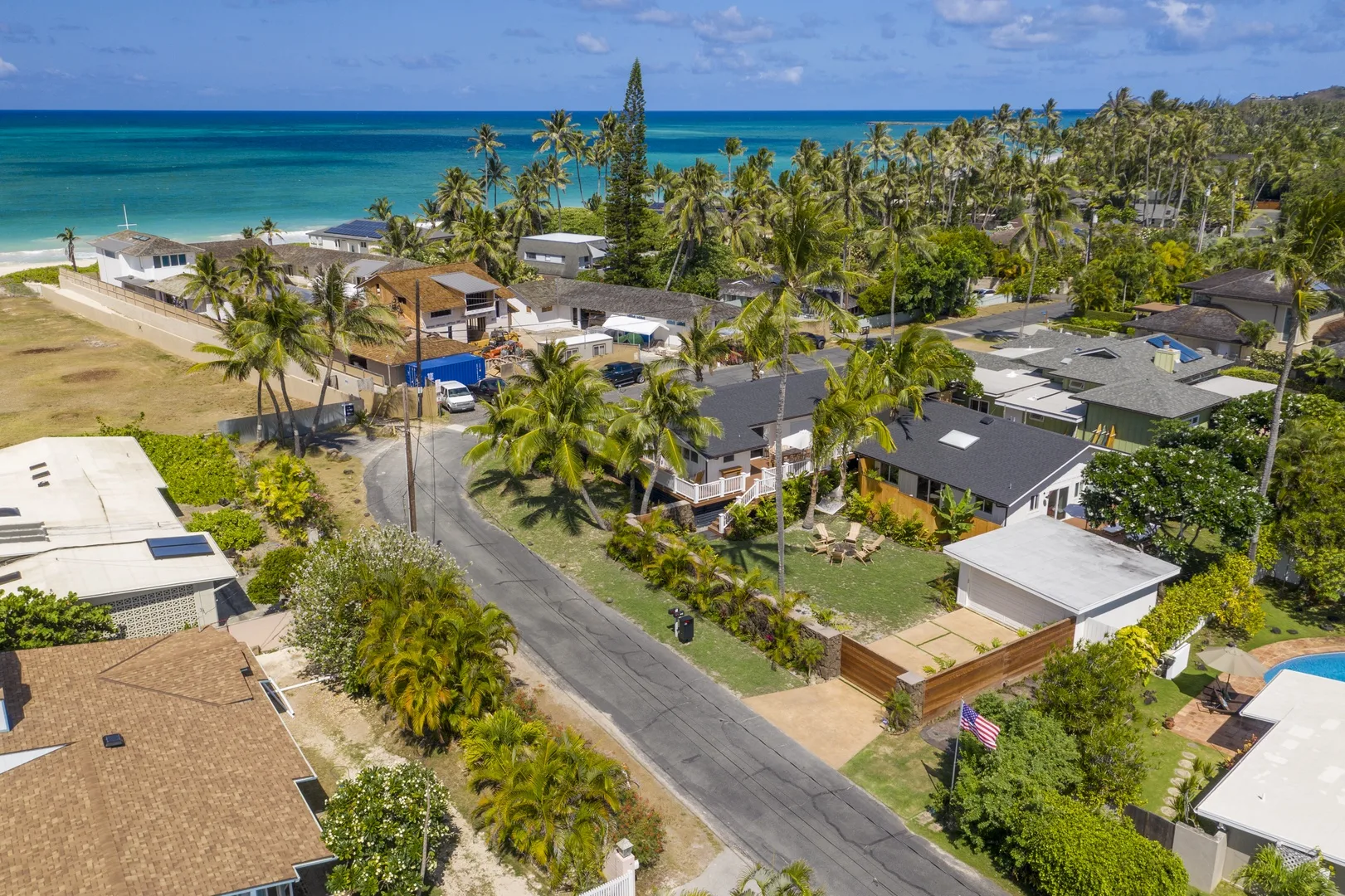 Aerial view of a coastal neighborhood with homes, palm trees, and the ocean.