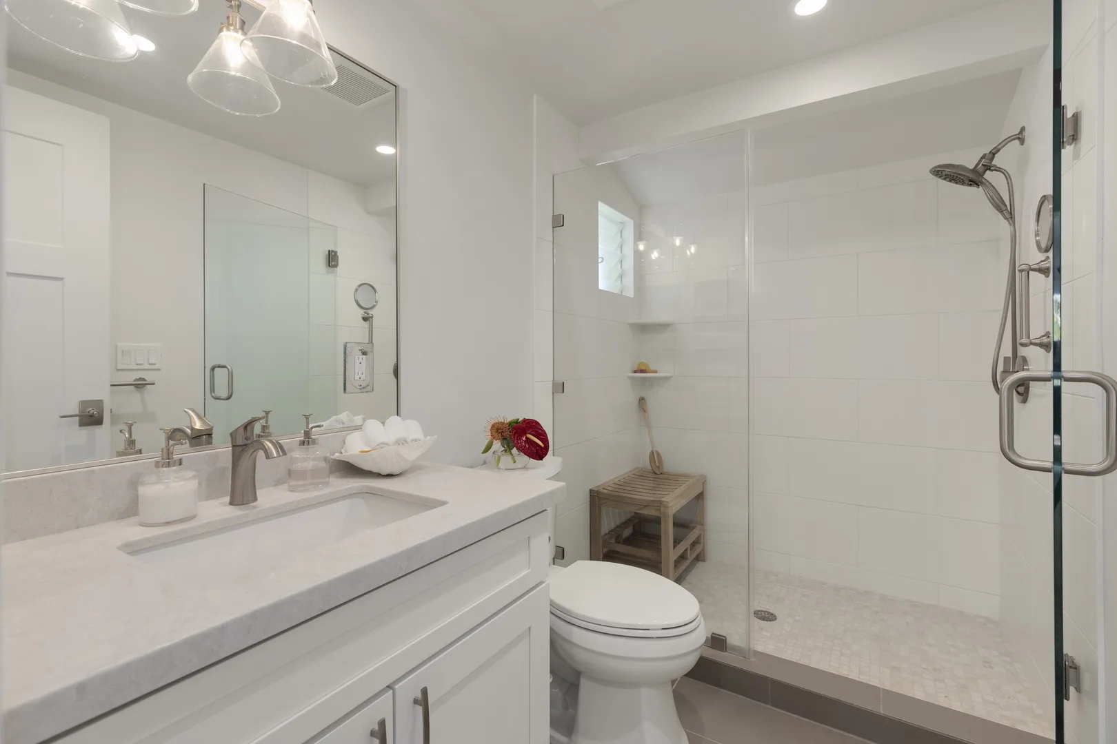 A bright bathroom with a wide vanity and glass-enclosed shower.