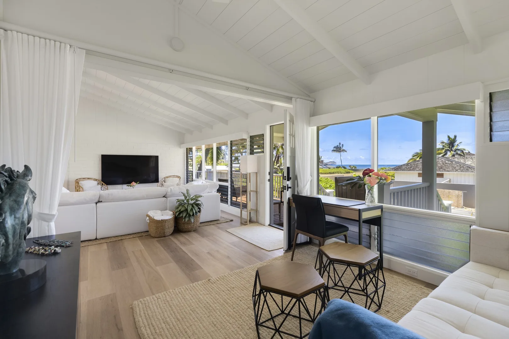 A bright living room opens onto a balcony with an ocean view.