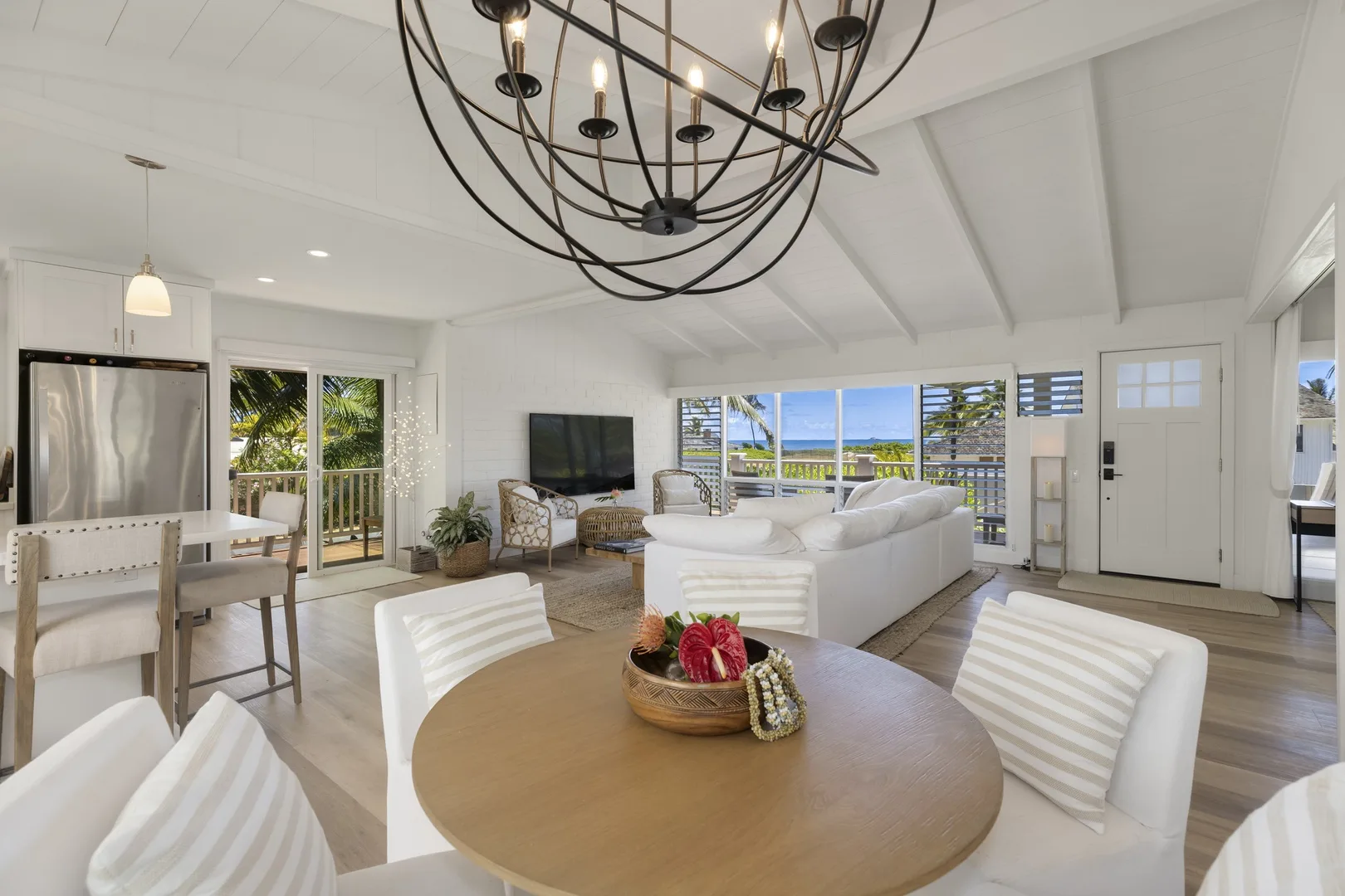 A bright living and dining area with white seating and broad windows.