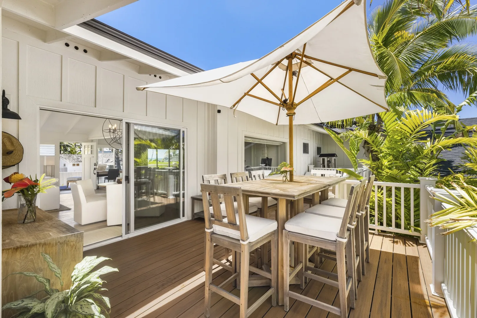 An outdoor dining area with a wooden table and chairs beneath a large umbrella.