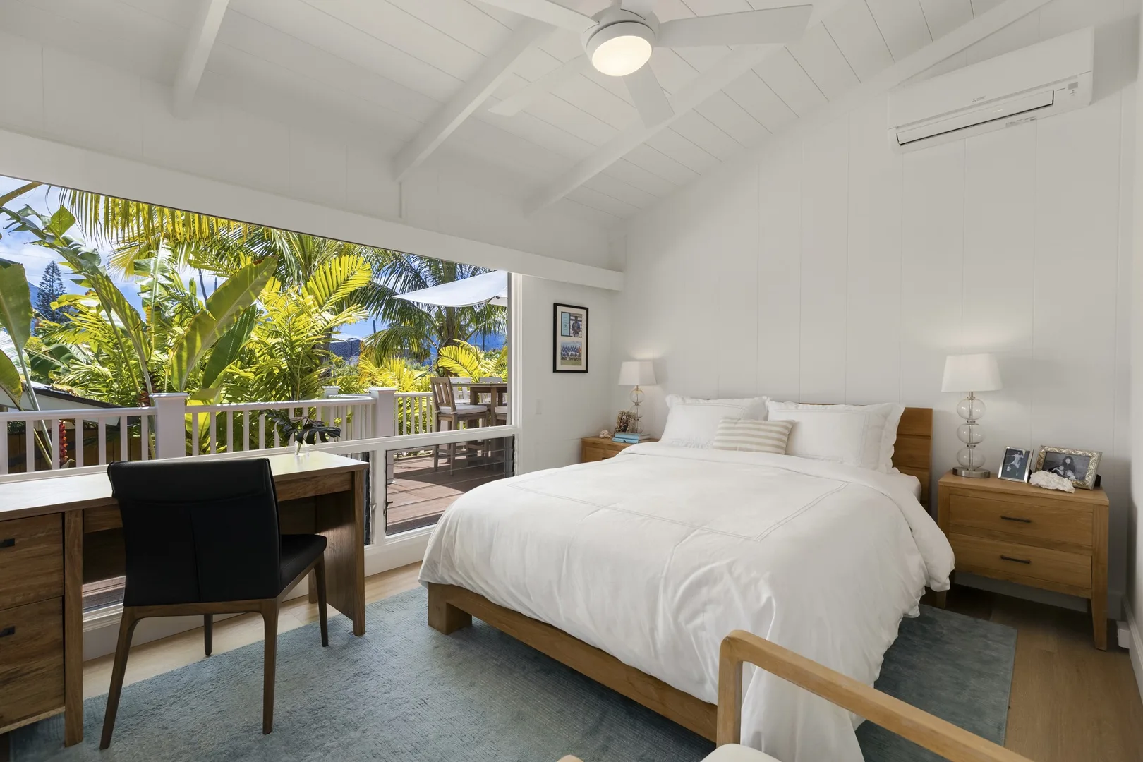 A bright bedroom with a large bed and wide windows overlooking greenery.
