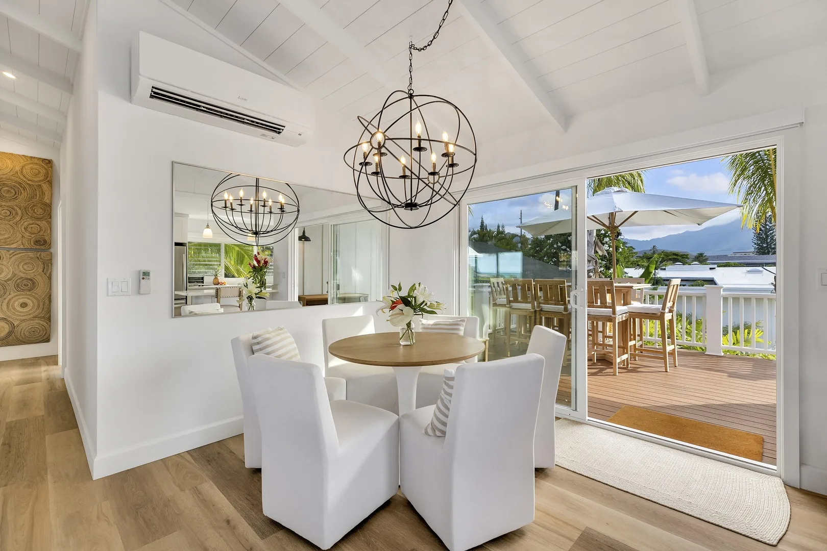 A bright dining area opens onto a deck with outdoor seating and a water view.