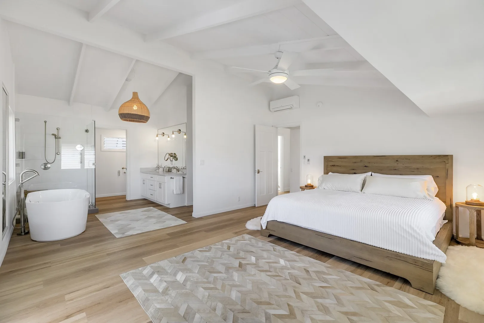 A bright bedroom with a bed and an open bathroom area.