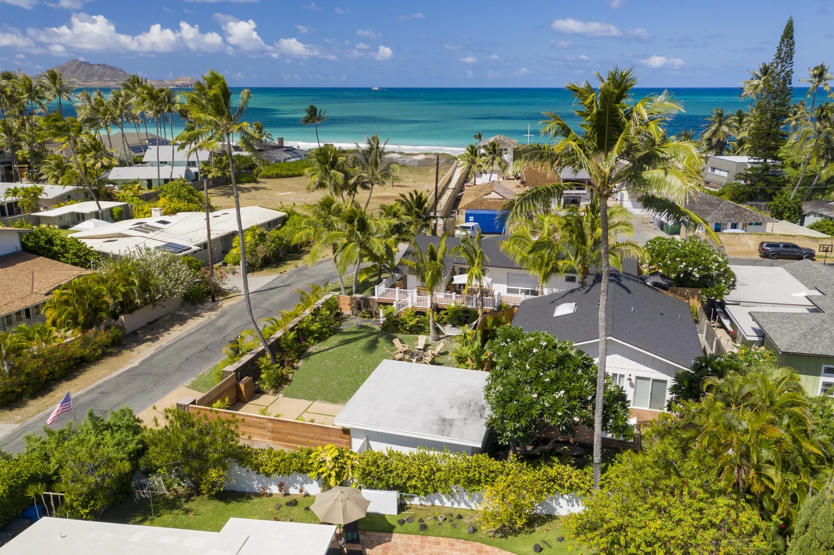 Aerial view of a tropical coastal neighborhood with homes, palm trees, and ocean.