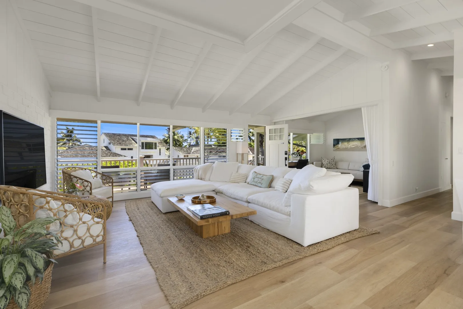 A bright living room with white seating, a woven rug, and wide windows.