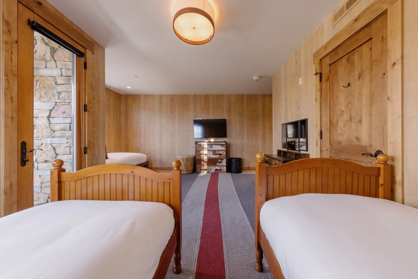 A wood-paneled bedroom with two beds and a television.