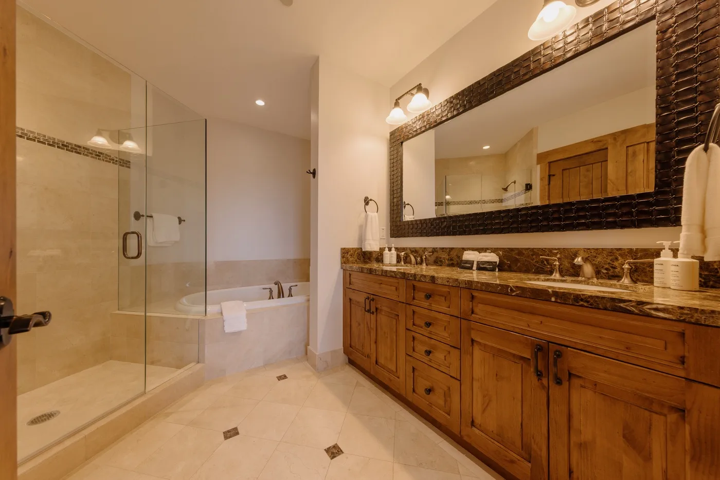 A bathroom with a glass shower, bathtub, and wooden vanity.