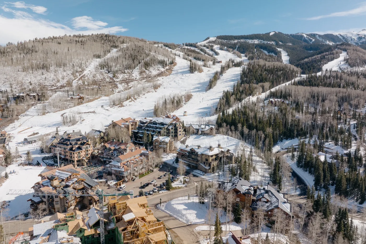 Aerial view of a snowy mountain resort with ski runs and buildings.