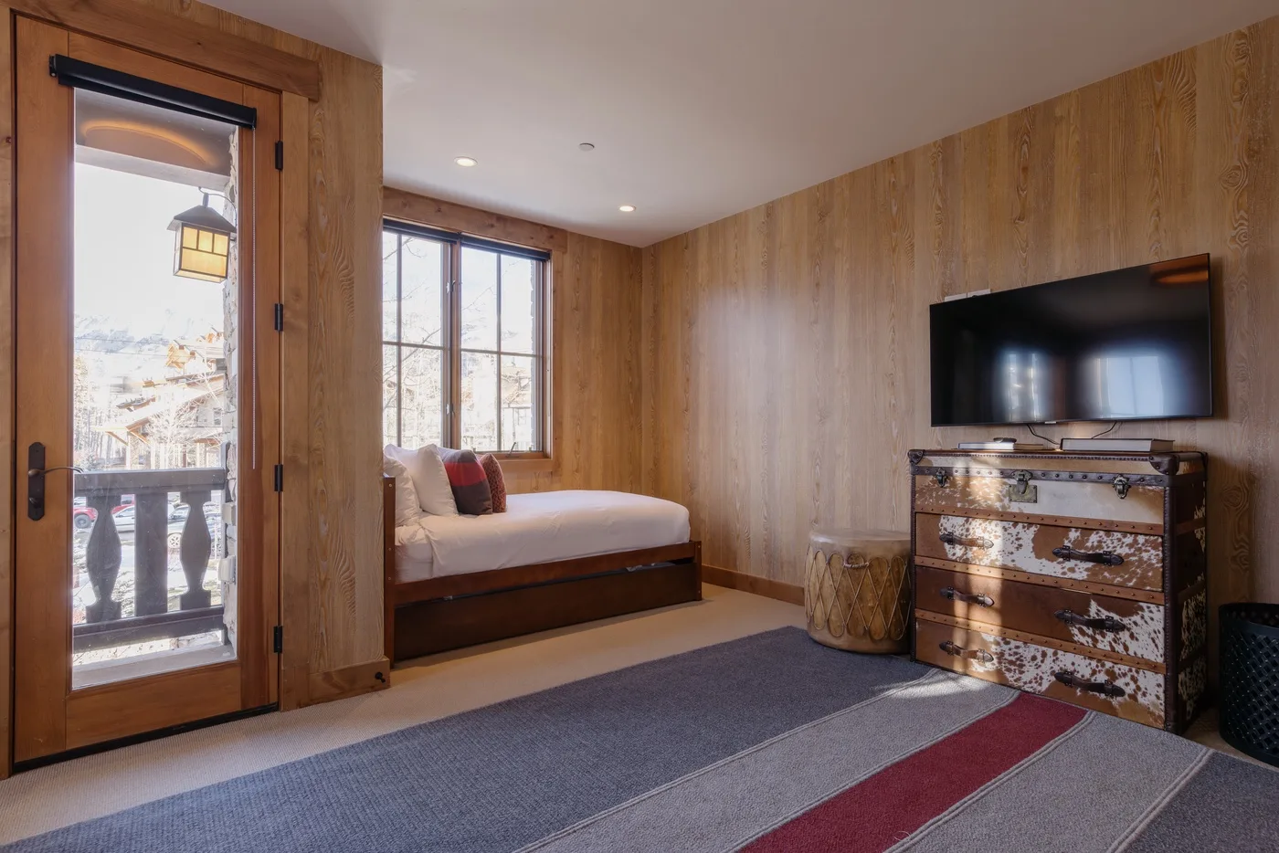 A bedroom with a bed beneath the window and a television on the wall.