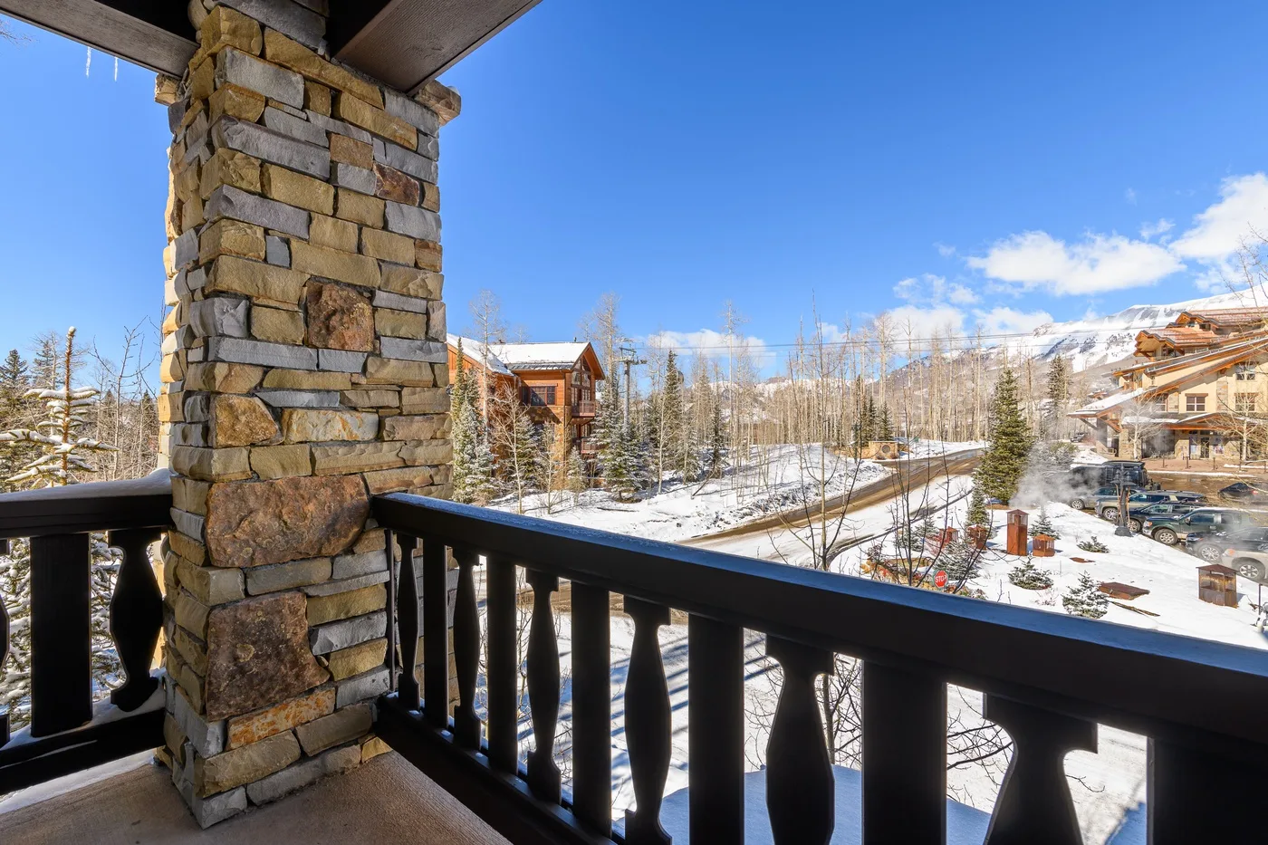 A covered balcony overlooks snow-covered homes and a mountain landscape.
