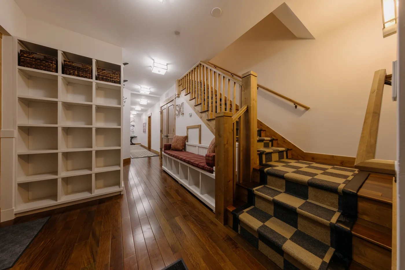 A warm interior hallway with wooden stairs and built-in shelving.