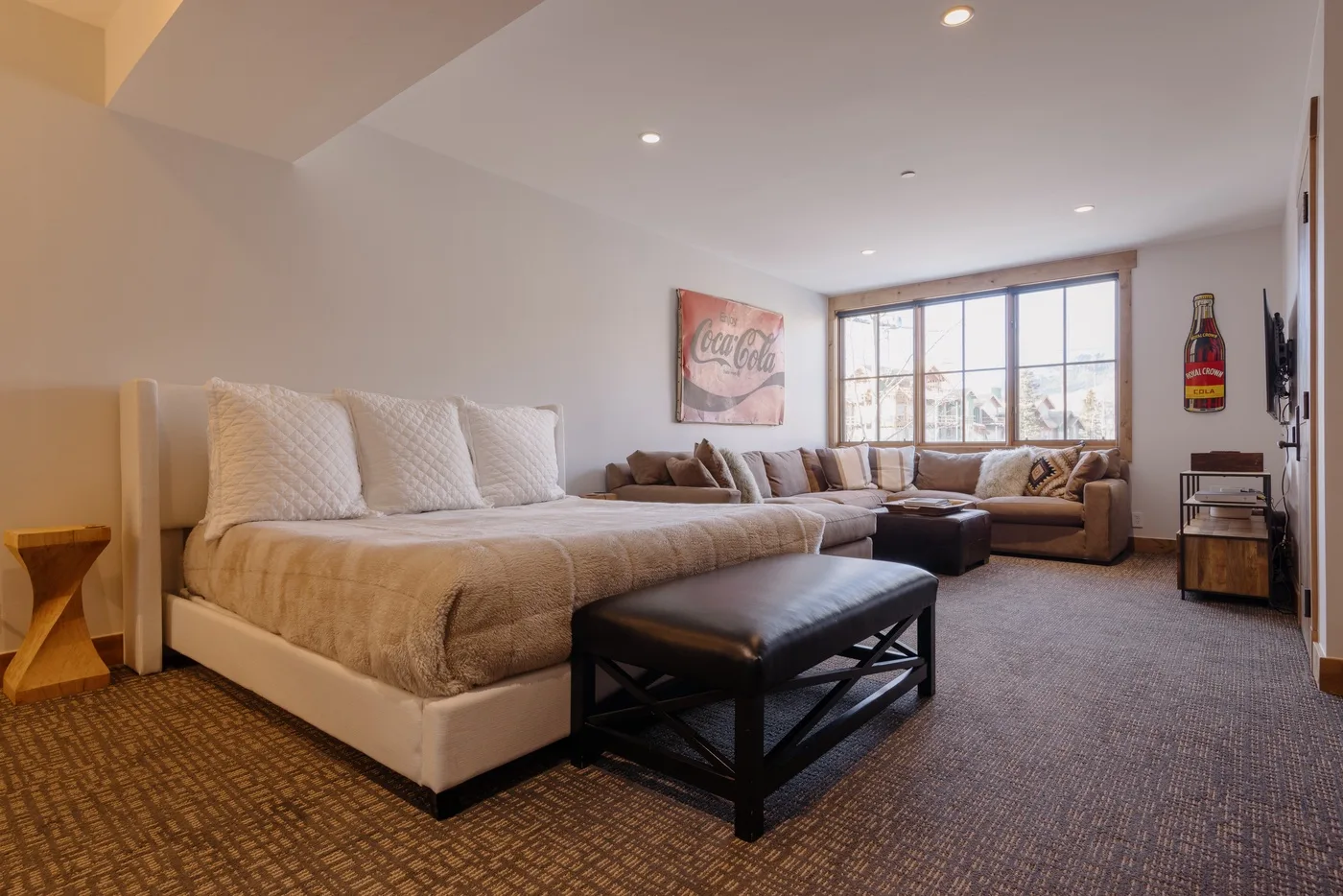 A spacious bedroom with a large bed, seating area, and wide windows.
