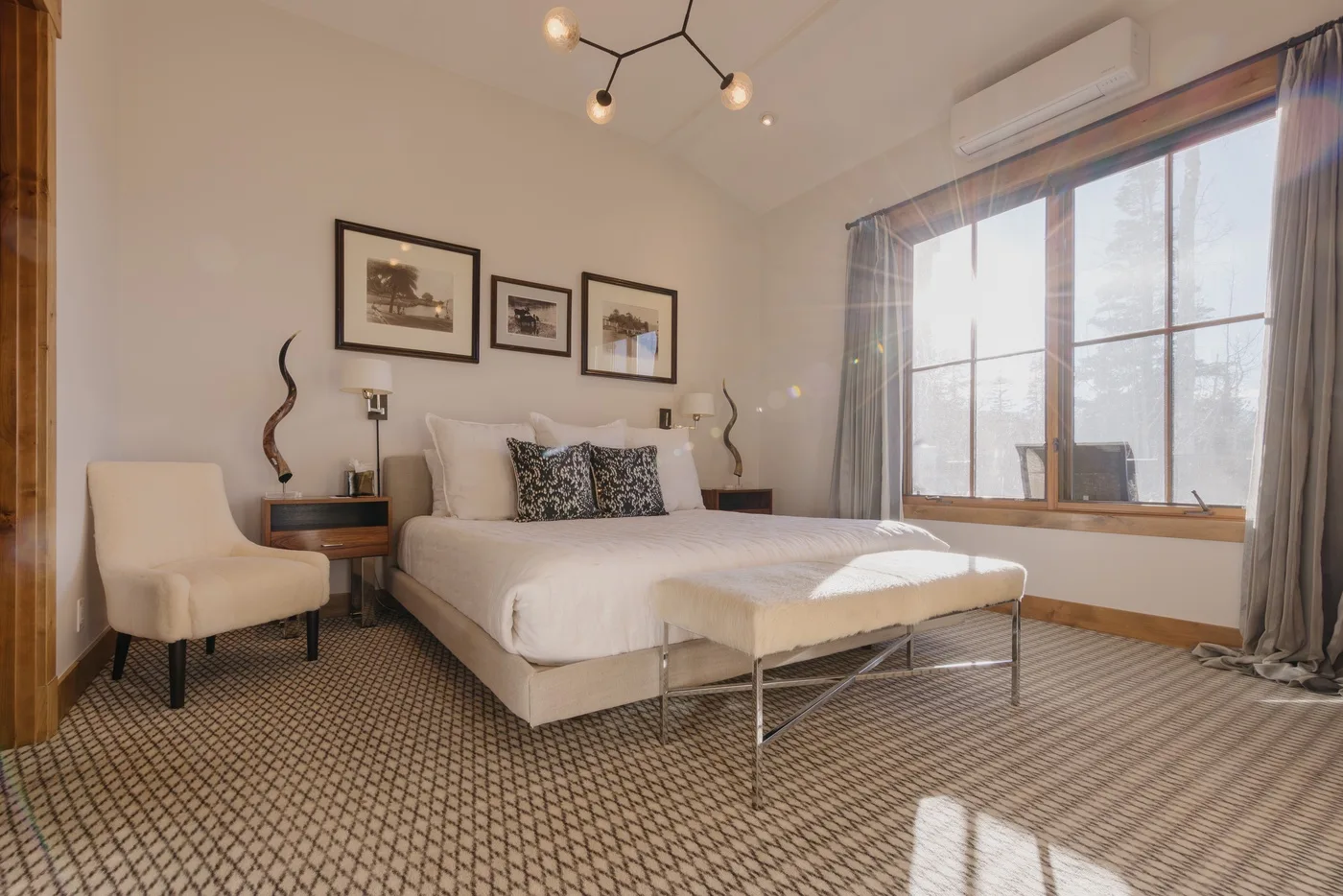 A bedroom with a bed, framed wall art, and a large window.