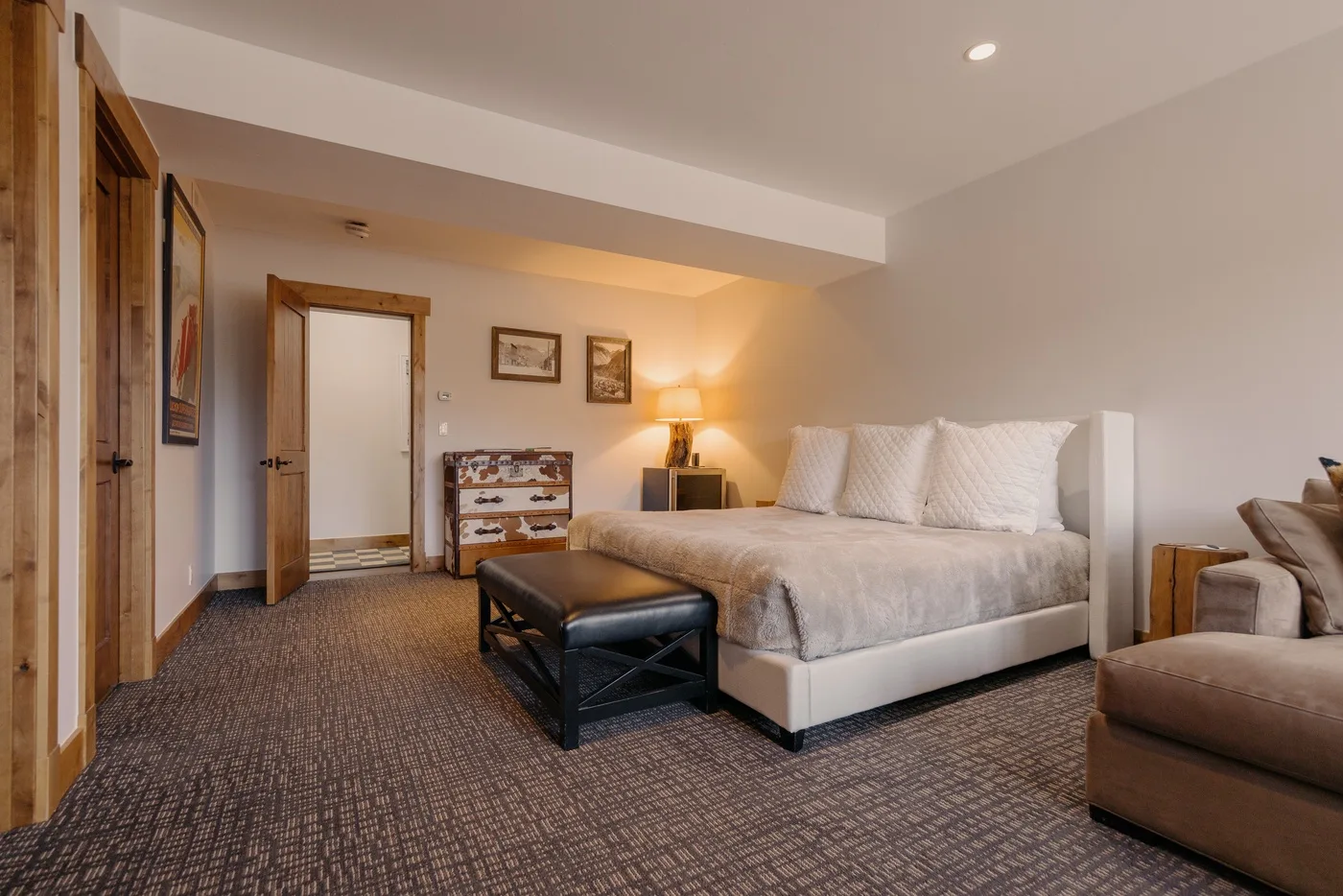 A bedroom with a bed, a bench, and a seating area.