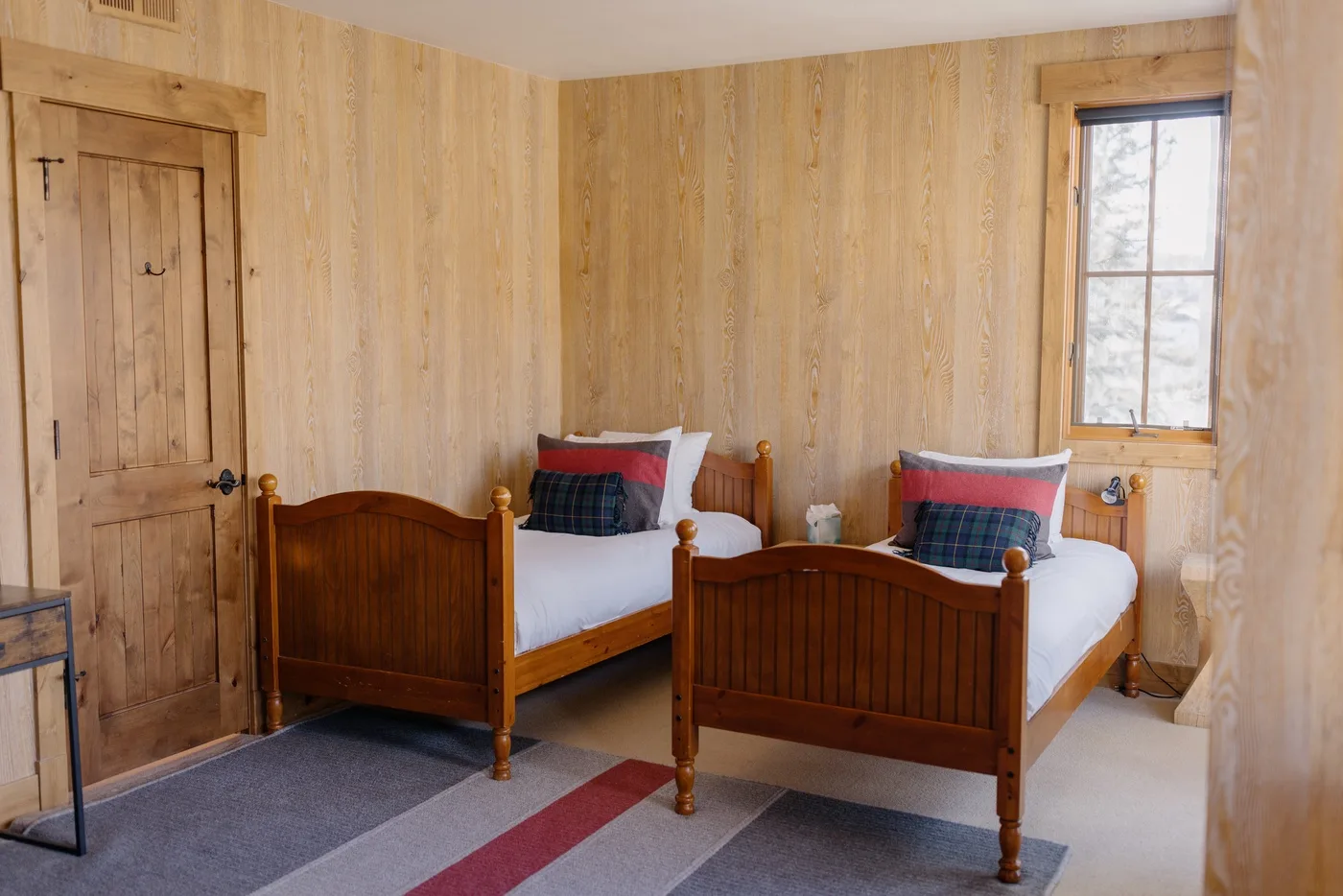 A wood-paneled bedroom with two single beds and a window.