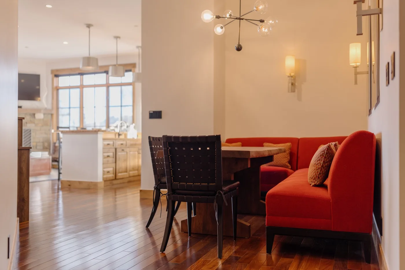 A dining and living area with a table, dark chairs, and red seating.