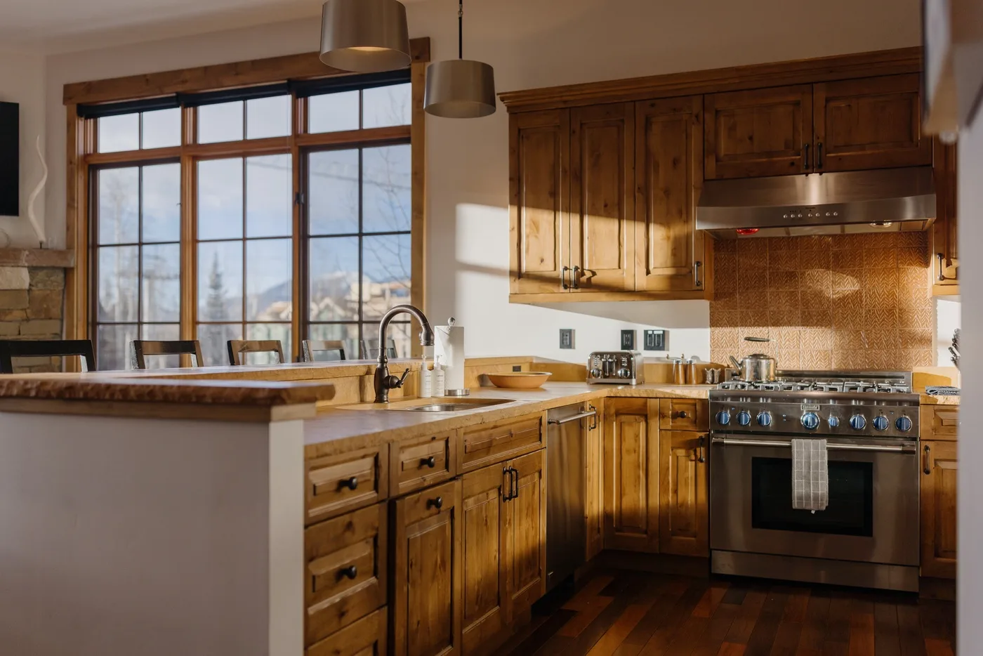 A warm kitchen with wooden cabinets, a central island, and a large window.