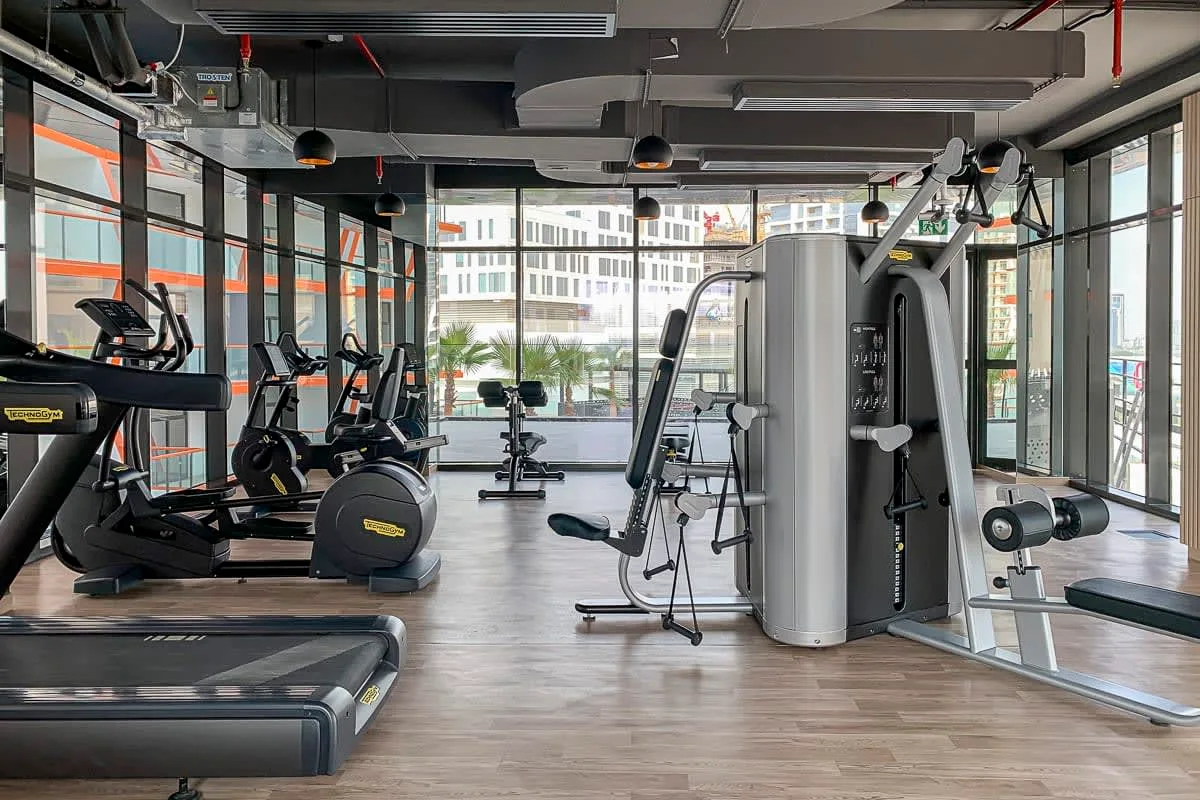 A gym with exercise machines and large windows.