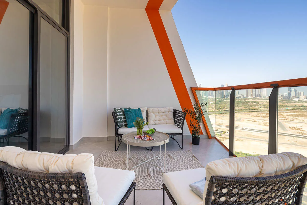 A balcony seating area has cushioned chairs, a small table, and a glass railing.