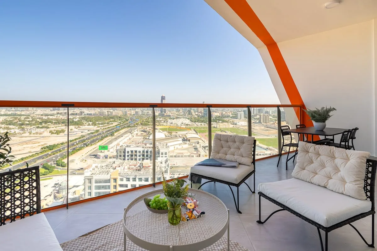 A balcony seating area overlooks the city, with a small table between the seats.